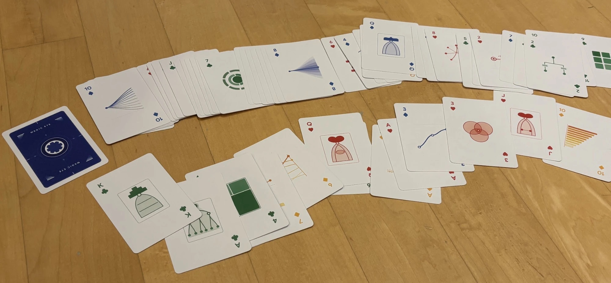 A deck of playing cards spread across a wooden floor. Each card carries a different small data visualization, in blue, red, green, and yellow.